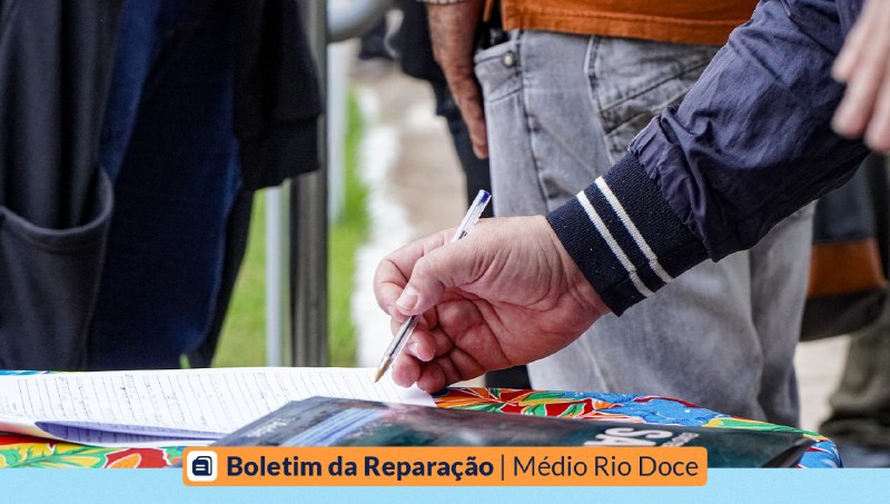 Imagem de um homem assinando um papel. Outras pessoas estão presentes.